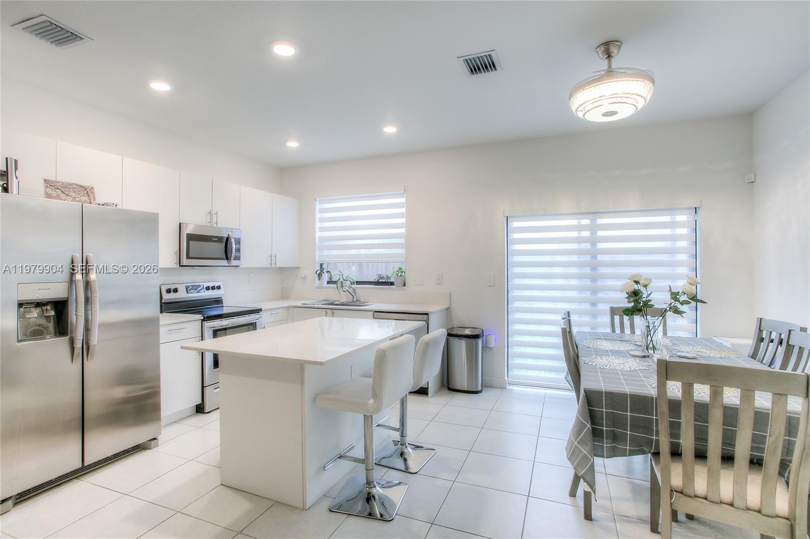 11849 Southwest 247th Terrace Homestead, FL 33032 - Photo 8 of 13 a kitchen with a table chairs microwave and refrigerator