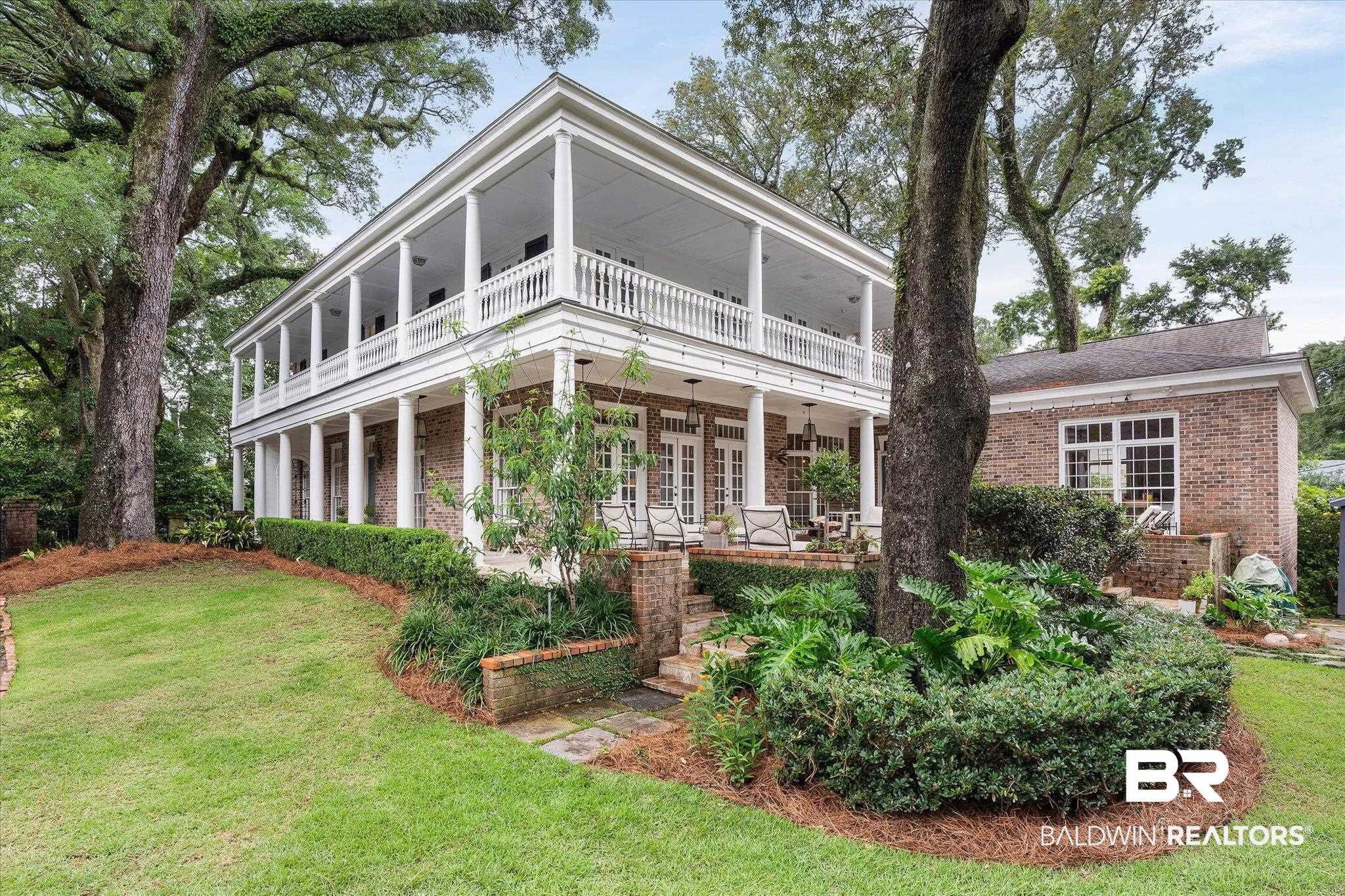 3908 Yester Place Mobile, AL 36608 - Photo 36 of 45 Colonial-style brick residence featuring a two-story wrap-around porch with white columns and balustrades