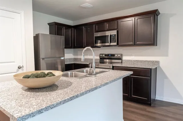 a kitchen with stainless steel appliances granite countertop a sink a stove a refrigerator and cabinets