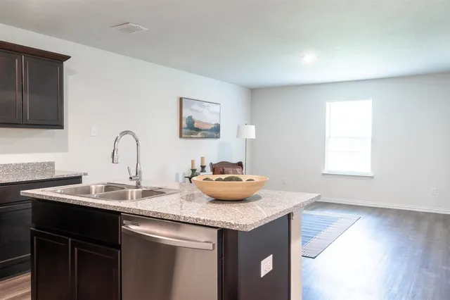 a living room with stainless steel appliances furniture and a kitchen view