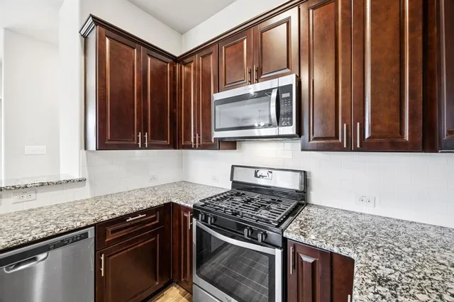 a kitchen with stainless steel appliances granite countertop cabinets and a stove top oven