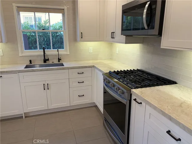 a kitchen with white cabinets and window