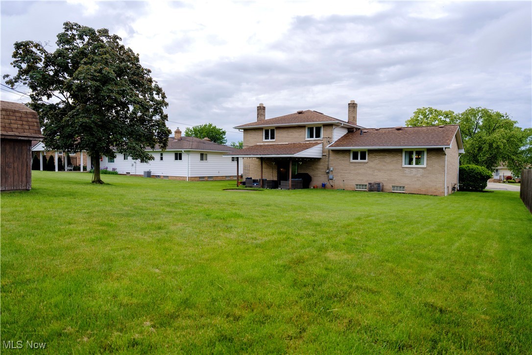 594 Long Ridge Drive Independence, OH 44131 - Photo 31 of 36 Rear view of property featuring a lawn, brick siding, roof with shingles, and a chimney