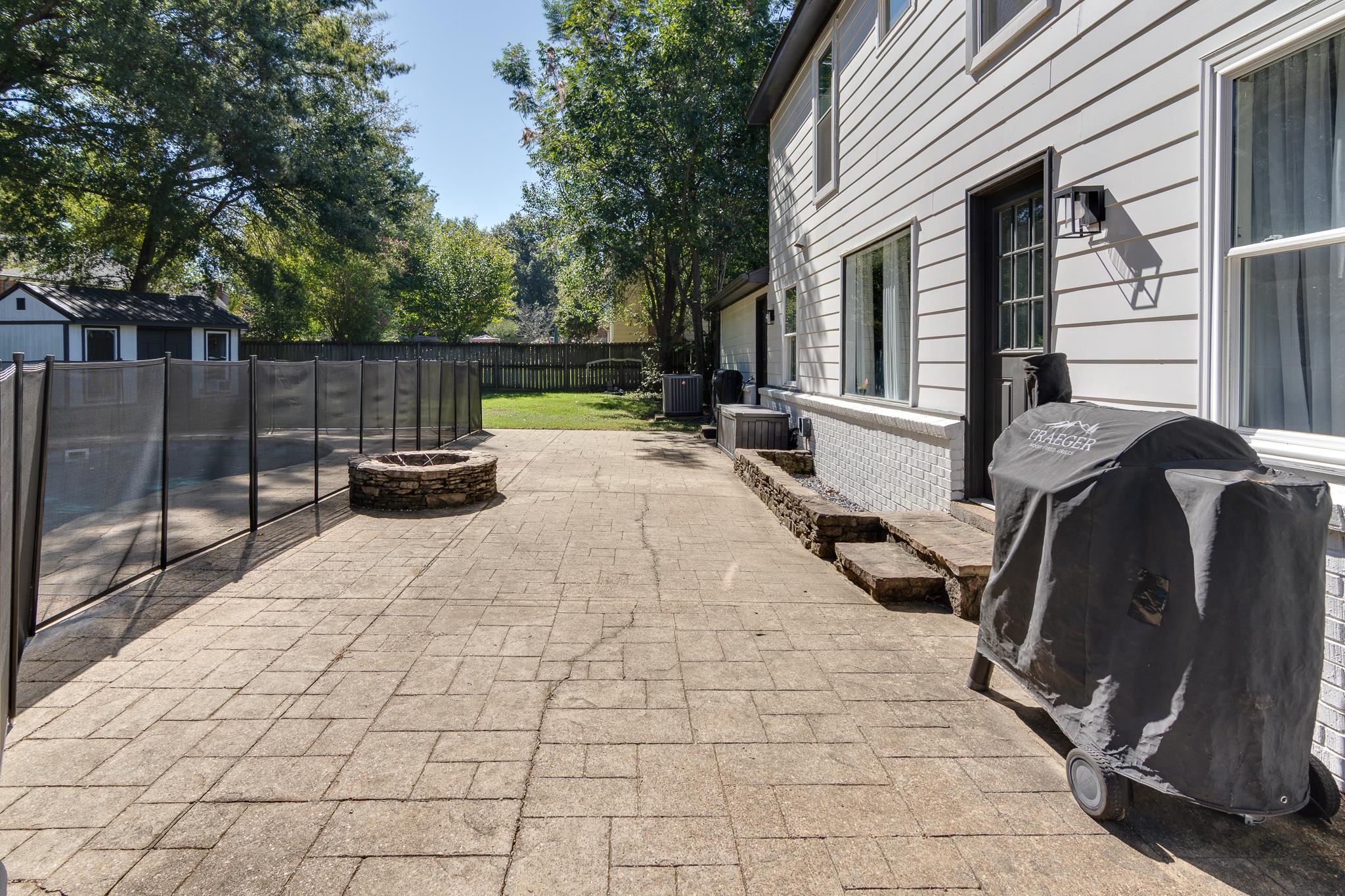 608 King Ridge Cove Collierville, TN 38017 - Photo 27 of 29 Stamped concrete patio with a stone fire pit, fenced pool area, and a storage shed