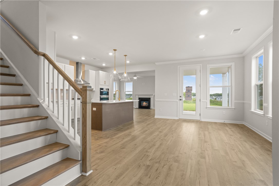 631 Sweetspire Trail, Unit 148 Seneca, SC 29678 - Photo 4 of 36 Hardwood floors stretch across this open-concept living area, featuring a modern kitchen island and a cozy fireplace.