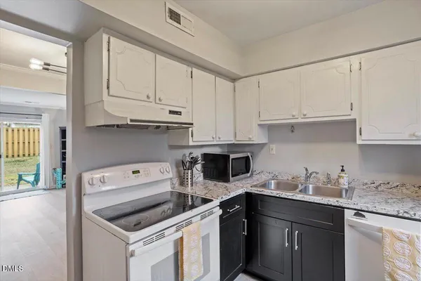 a kitchen with stainless steel appliances granite countertop white cabinets and a refrigerator