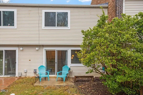 a backyard of a house with table and chairs and potted plants