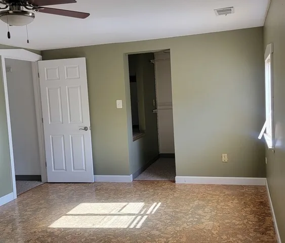 an empty room with windows and fan