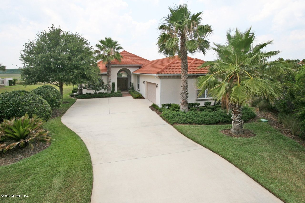 a view of a house with a small yard and palm trees