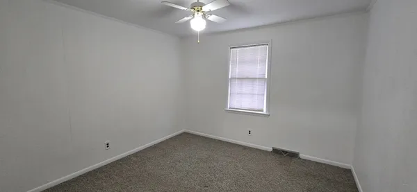 an empty room with a window and a fan