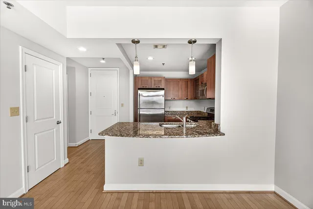 a room with kitchen island a sink a stove and wooden floor