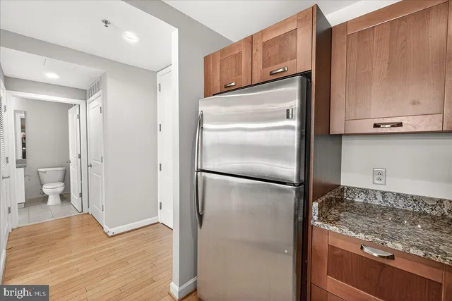 a kitchen with metallic refrigerator freezer and a wooden floor