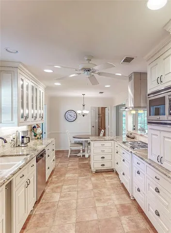 a large white kitchen with a large window and stainless steel appliances
