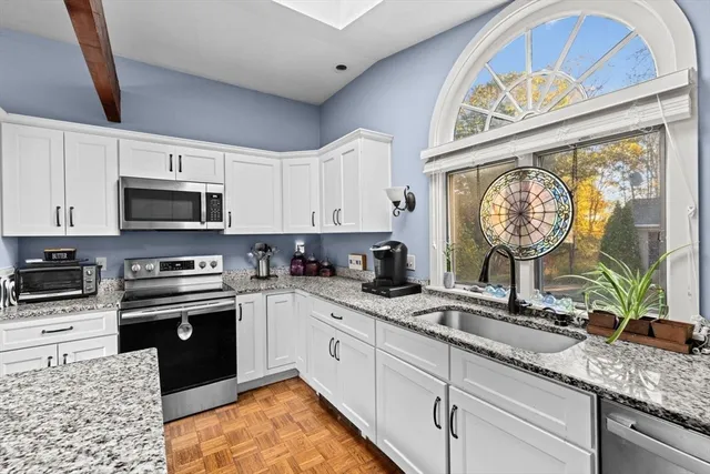 a kitchen with granite countertop a stove a sink and a microwave