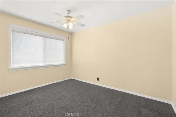 an empty room with a window and a fan