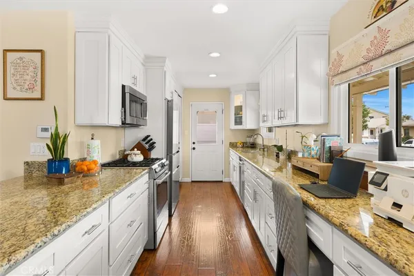a kitchen with stainless steel appliances granite countertop sink stove refrigerator and cabinets