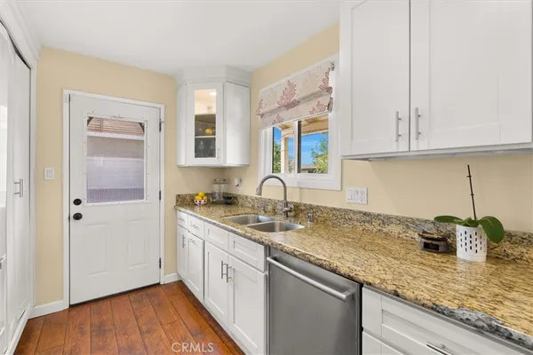 a kitchen with stainless steel appliances granite countertop a sink dishwasher a refrigerator and wooden cabinets with wooden floor