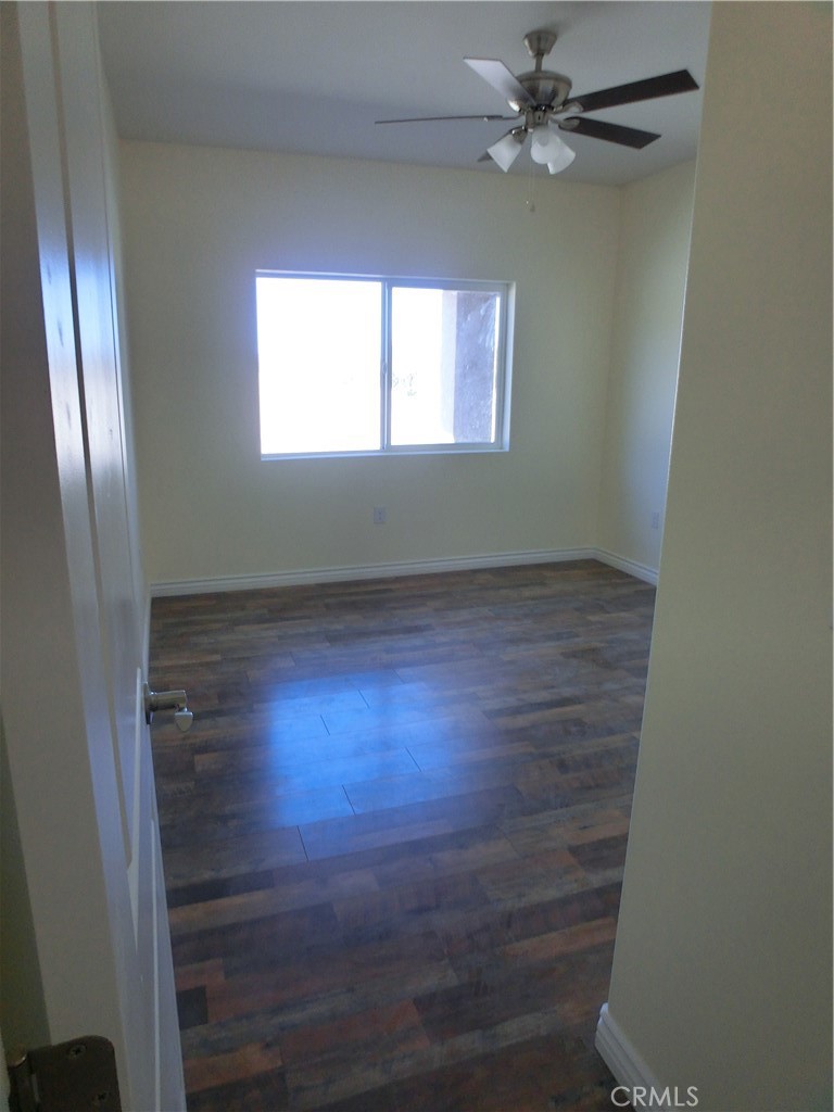 11462 Prado Road Pinon Hills, CA 92372 - Photo 12 of 18 a view of an empty room with wooden floor and a window