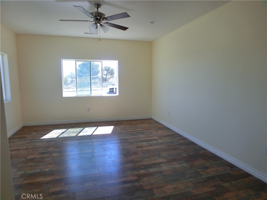 11462 Prado Road Pinon Hills, CA 92372 - Photo 13 of 18 an empty room with wooden floor chandelier fan and windows
