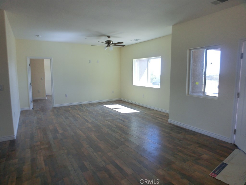 11462 Prado Road Pinon Hills, CA 92372 - Photo 18 of 18 an empty room with wooden floor fan and windows