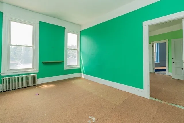 a view of a hallway with wooden floor and a bathroom