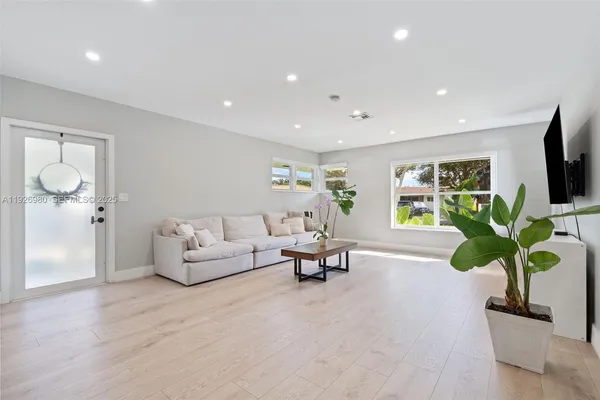 a living room with furniture a potted plant and a flat screen tv