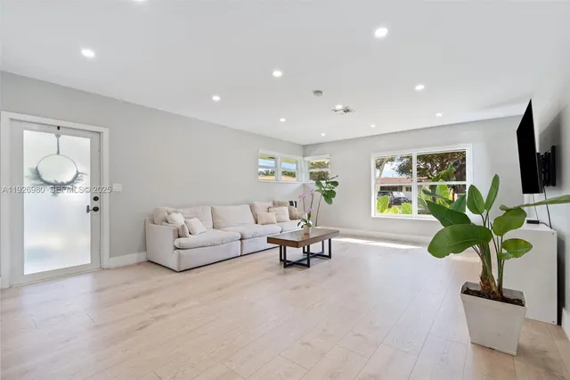 a living room with furniture a potted plant and a flat screen tv