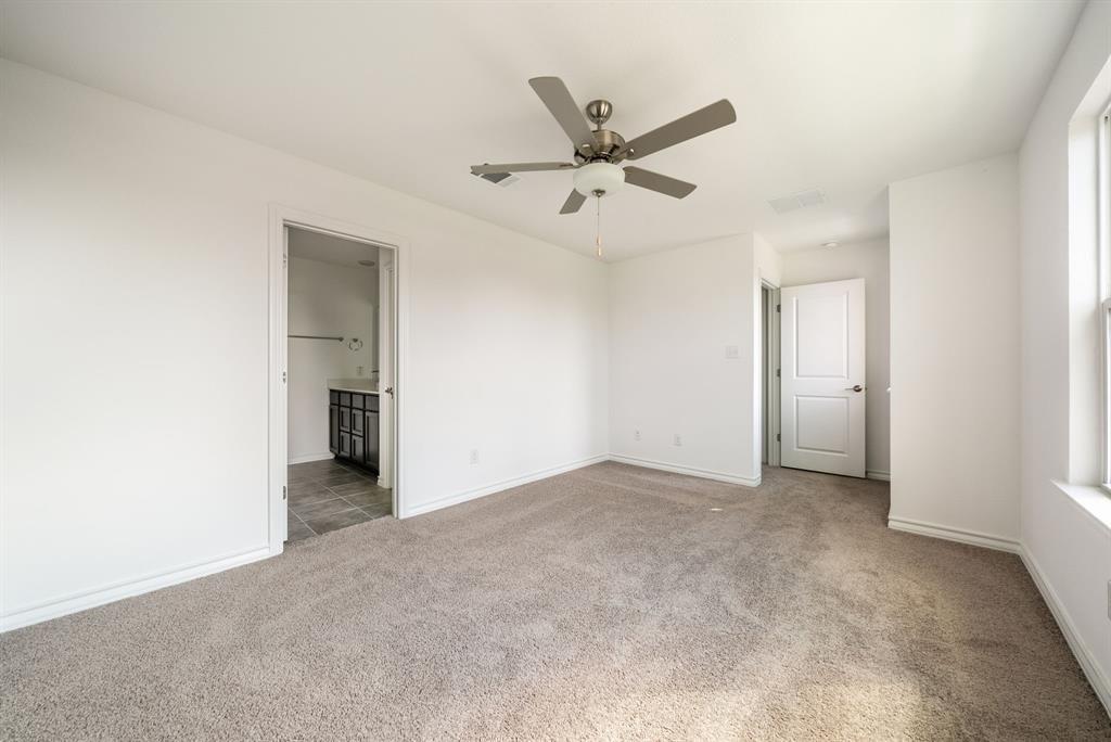 123 Watkinville Road Hutto, TX 78634 - Photo 10 of 30 Unfurnished bedroom with light colored carpet, ceiling fan, and connected bathroom