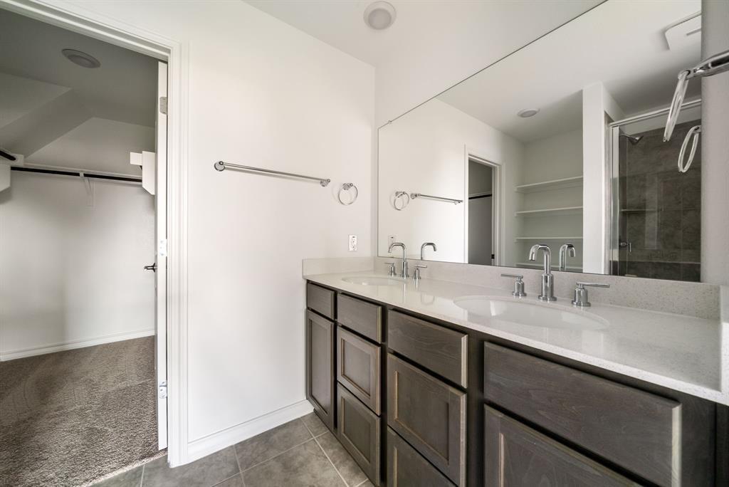 123 Watkinville Road Hutto, TX 78634 - Photo 12 of 30 Full bath with a spacious closet, double vanity, dark tile patterned floors, a stall shower, and dark colored carpet