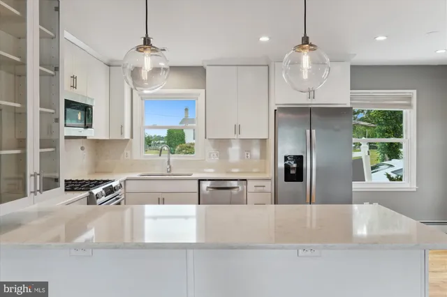 a large kitchen with stainless steel appliances granite countertop a sink a oven a refrigerator and a white cabinets