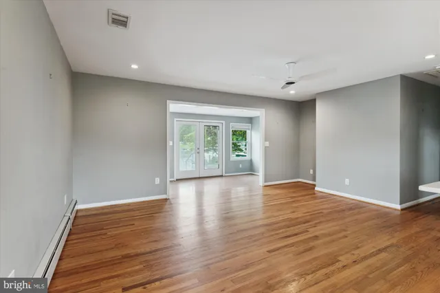 a view of an empty room with wooden floor and windows