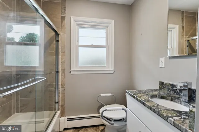 a bathroom with a granite countertop toilet a sink and a mirror