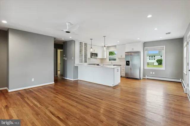 a view of an empty room with window and wooden floor