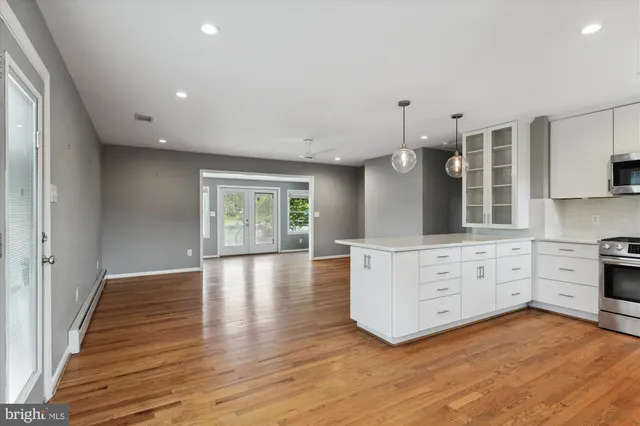 a large kitchen with granite countertop a large counter top space a sink stainless steel appliances and cabinets