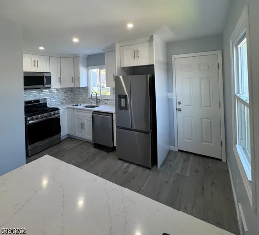 a kitchen with stainless steel appliances granite countertop a refrigerator and a stove top oven