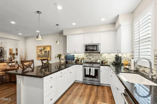 a very nice looking kitchen with granite countertop a sink counter top space appliances and cabinets