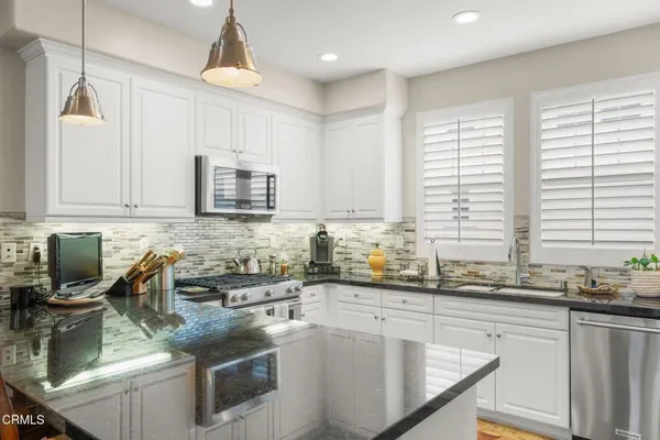 a kitchen with a sink a counter top space cabinets and stainless steel appliances