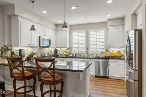 a kitchen with stainless steel appliances granite countertop a table chairs sink refrigerator and microwave