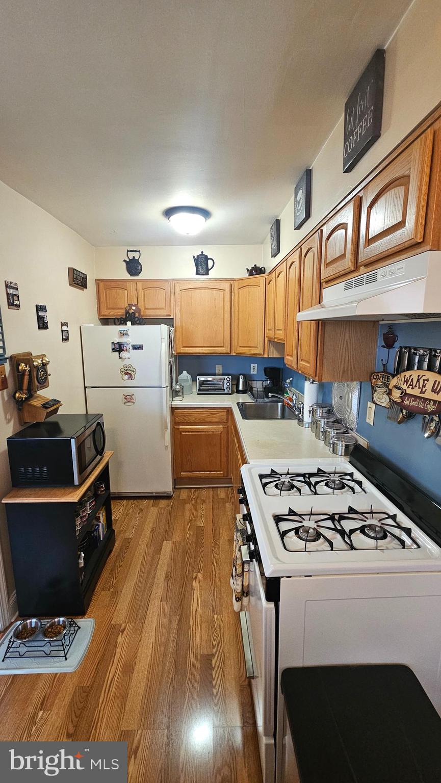 7829 Horrocks Street Philadelphia, PA 19152 - Photo 17 of 46 a kitchen with granite countertop a stove a sink dishwasher and a dining table with wooden floor
