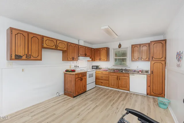 a large kitchen with stainless steel appliances granite countertop a stove top oven a sink dishwasher and wooden cabinets with wooden floor