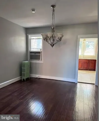 an empty room with wooden floor chandelier and windows