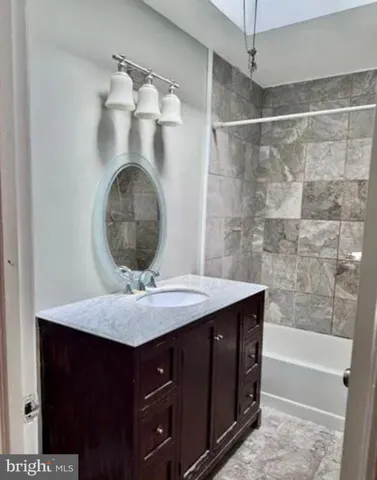 a bathroom with a granite countertop sink a mirror and shower