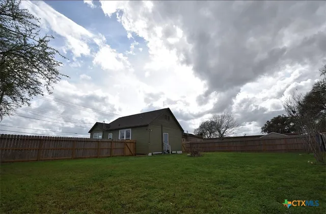 a backyard of a house with lots of green space and wooden fence