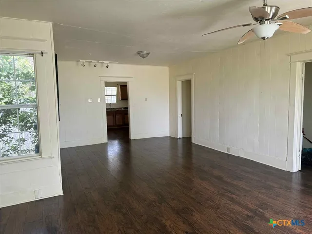 an empty room with wooden floor cabinet and windows