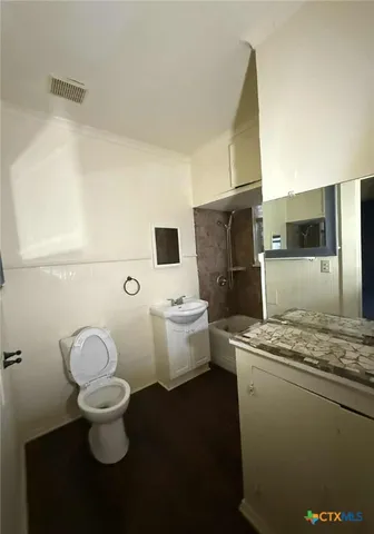 a bathroom with a granite countertop toilet and a sink