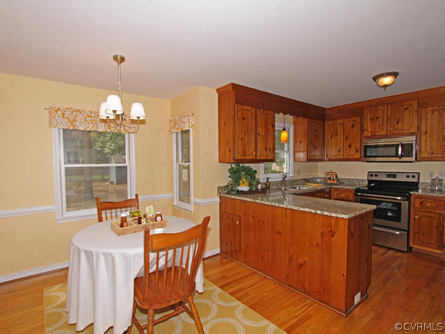 5513 Gatebridge Road North Chesterfield, VA 23234 - Photo 8 of 24 a kitchen with stainless steel appliances granite countertop a stove top oven a sink dishwasher a dining table and chairs with wooden floor