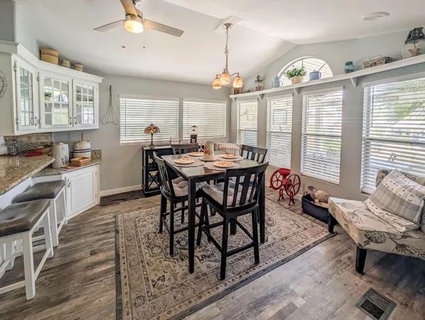 a dining room with wooden floor a chandelier a wooden table and chairs