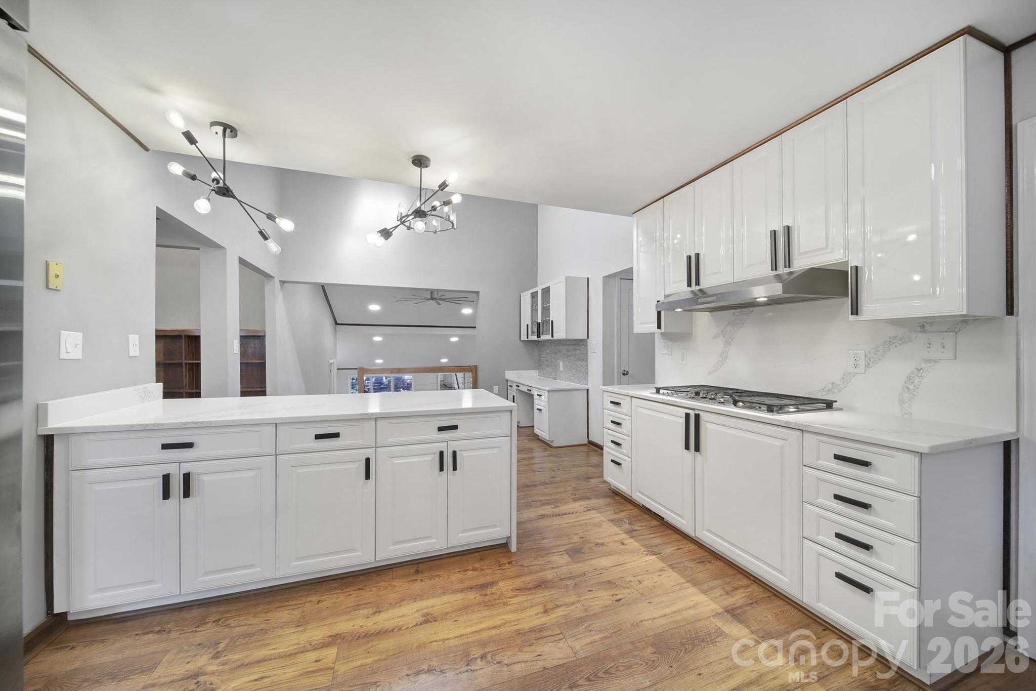 7005 Tega Cay Drive Tega Cay, SC 29708 - Photo 12 of 48 a large white kitchen with granite countertop a stove top oven a sink a window and white cabinets