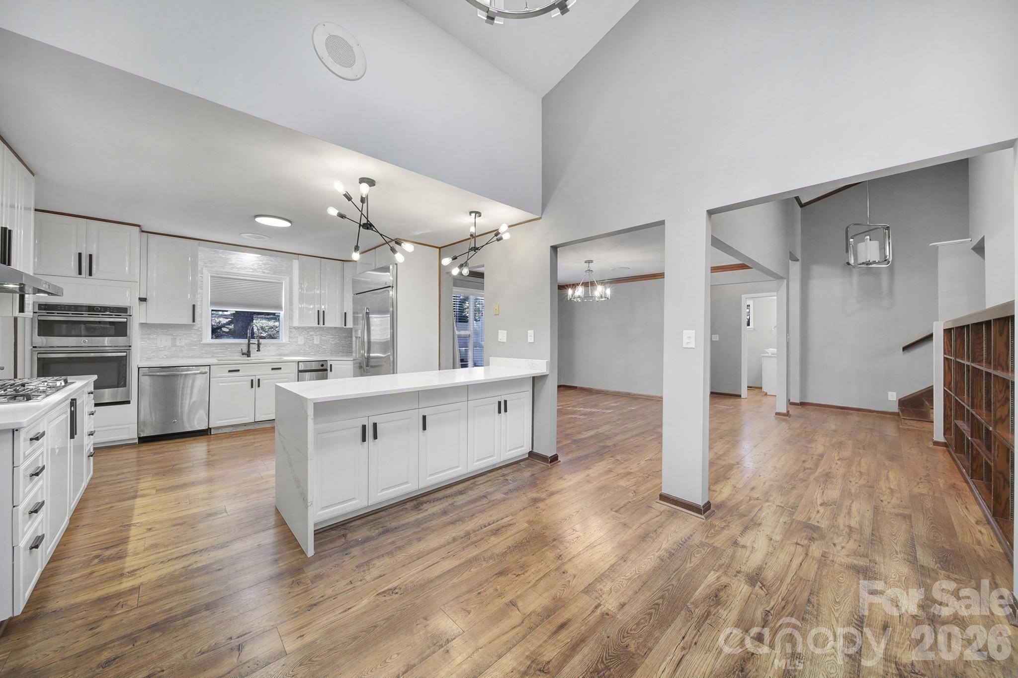 7005 Tega Cay Drive Tega Cay, SC 29708 - Photo 13 of 48 a large white kitchen with kitchen island a sink a stove and white cabinets