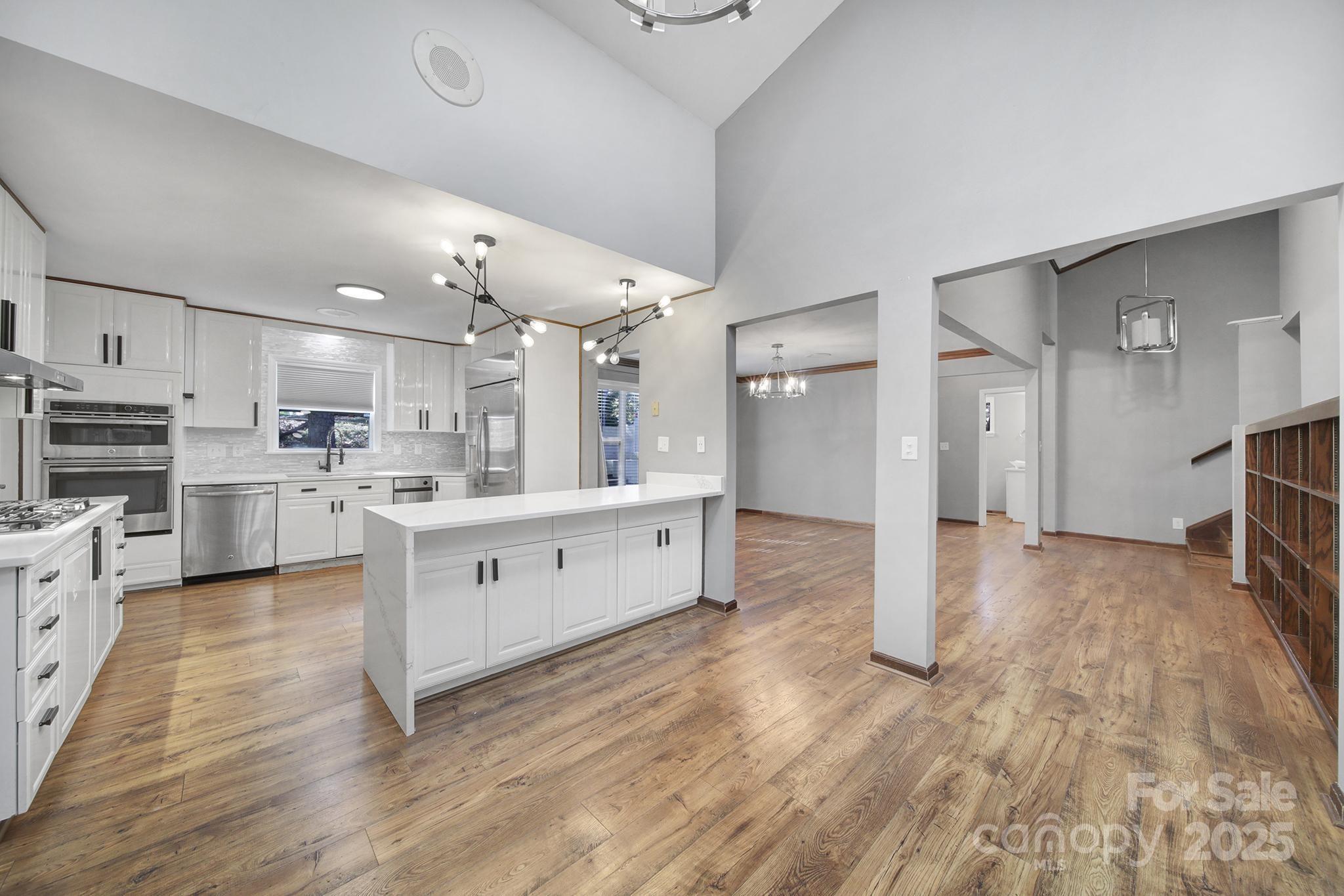 7005 Tega Cay Drive Tega Cay, SC 29708 - Photo 15 of 48 a large white kitchen with kitchen island a sink a stove and white cabinets